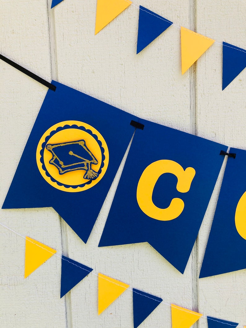 May include: A blue and gold graduation banner with the word "Congrats" and a graduation cap icon. The banner is strung with alternating blue and gold triangle flags.