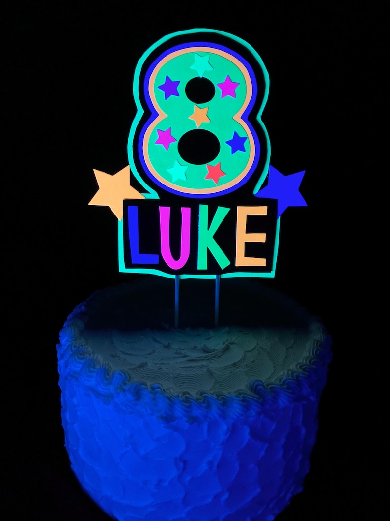 number 8 in neon green with LUKE in neon colors as a glow party birthday personalized cake topper that fluoresces under UV reflective black light