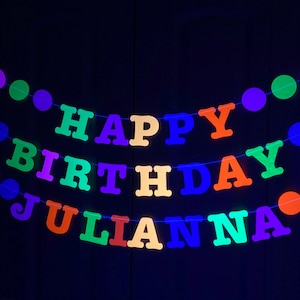 May include: A neon green, purple, orange, blue, and yellow banner with the words "Happy Birthday Juliana" strung on a string with colorful round dots.