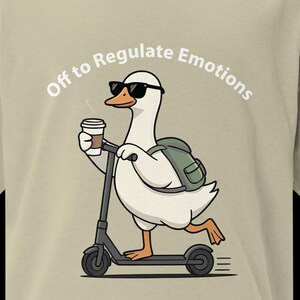 Può includere: T-shirt beige con un'oca dei cartoni animati con occhiali da sole e uno zaino, che va in scooter mentre tiene in mano una tazza di caffè. Il testo "Off to Regulate Emotions" è arcuato sopra l'oca. La maglietta ha maniche corte.