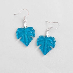 May include: A pair of turquoise blue leaf-shaped earrings with silver hooks.