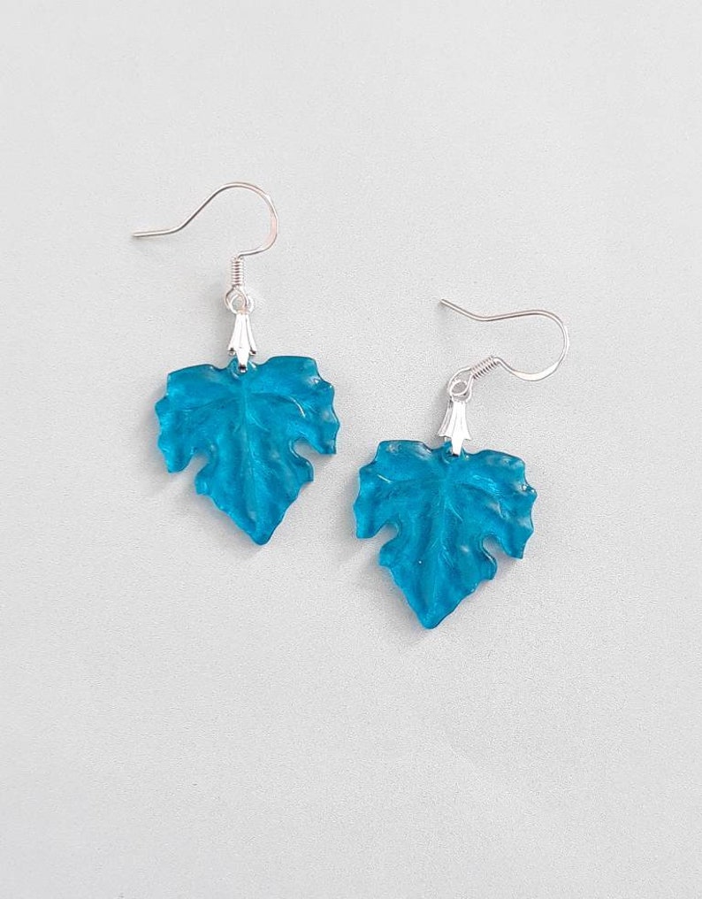 May include: A pair of turquoise blue leaf-shaped earrings with silver hooks.