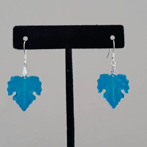 May include: A pair of turquoise blue leaf-shaped earrings with silver hooks.
