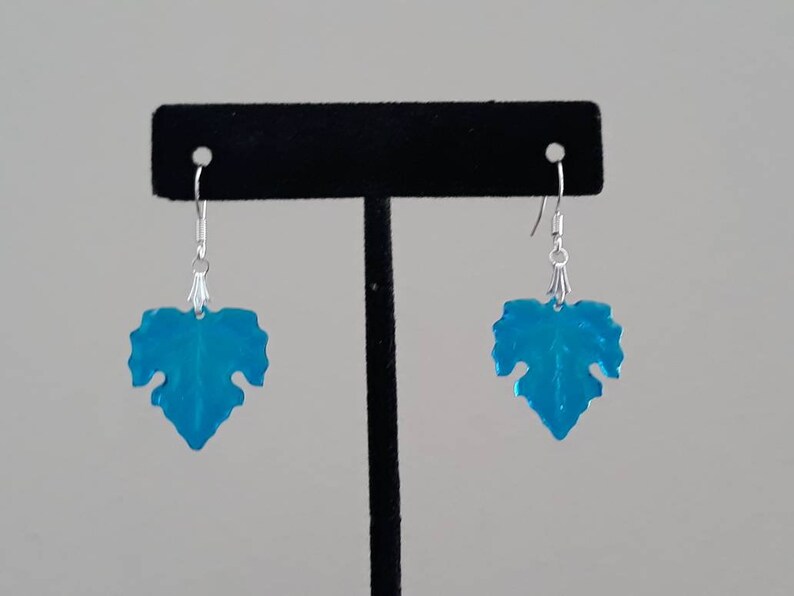 May include: A pair of turquoise blue leaf-shaped earrings with silver hooks.