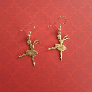 May include: A pair of gold-tone dangle earrings featuring a ballerina silhouette.