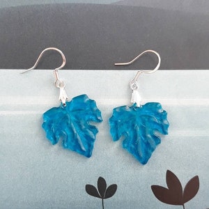 May include: A pair of blue leaf-shaped earrings with silver hooks.