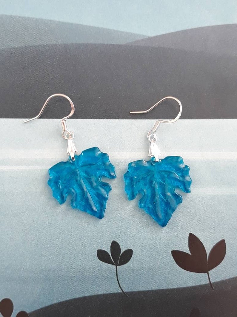 May include: A pair of blue leaf-shaped earrings with silver hooks.