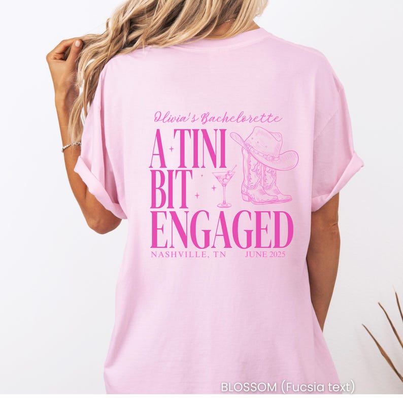 Pu&ograve; includere: T-shirt rosa chiaro con testo fucsia "Olivia's Bachelorette A Tini Bit Engaged". Il design include un cappello da cowboy, stivali e un bicchiere da cocktail. C'&egrave; anche scritto "Nashville, TN Giugno 2025".
