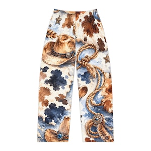 May include: Pants featuring a watercolor print of brown and white cowhide patterns, tan cowboy hats, coiled ropes, feathers, and small stars. The design includes blue and brown splotches on a white background, with detailed western motifs.