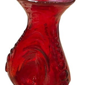 Könnte beinhalten: Eine rote Glasvase mit einer strukturierten Oberfläche und einer breiten Öffnung. Die Vase hat eine einzigartige, organische Form.