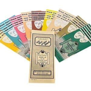 May include: A collection of vintage Max Factor pamphlets titled Hints on the Art of Make-Up, fanned out behind a central order blank. The booklets feature colorful covers with stylized face illustrations and text regarding stage and screen makeup.