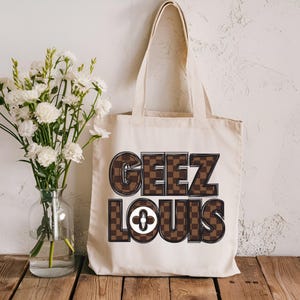 Pu&ograve; includere: Una borsa tote in tela bianca con testo stampato a scacchi marroni e neri che dice "Geez Louis".