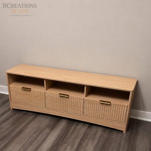 May include: A light wood media console featuring three open storage compartments above three drawers with vertical fluted detailing and horizontal brass-toned metal handles. The unit has a rectangular top surface and a clean, linear design.