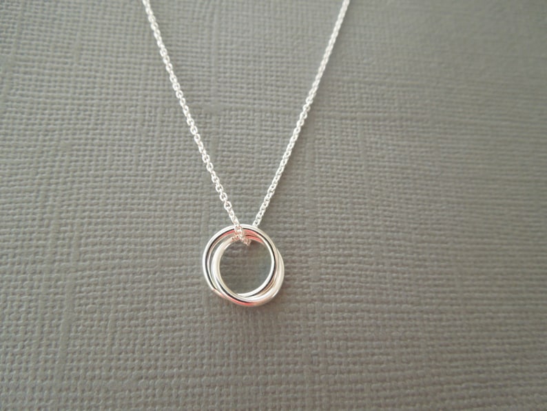 May include: A silver necklace with a double ring pendant. The pendant is made of two interlocking circles.