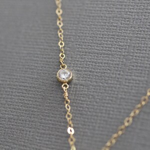 Puede incluir: Un delicado collar de cadena de oro con un solo colgante de cristal transparente.