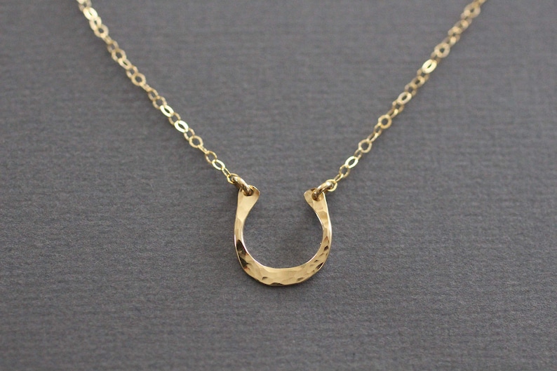 Peut inclure: Un collier en cha&icirc;ne dor&eacute;e avec un pendentif en forme de fer &agrave; cheval en or martel&eacute;.