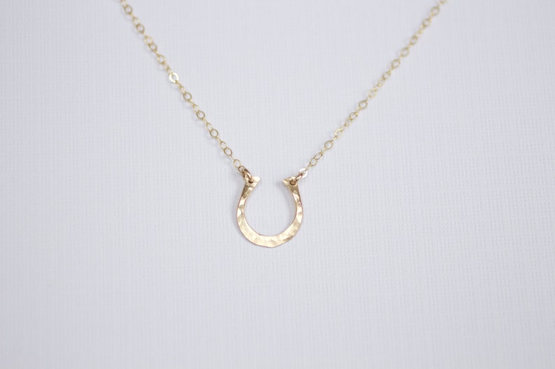Peut inclure: Un collier en or avec un pendentif en forme de fer &agrave; cheval martel&eacute;.