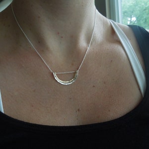May include: A silver necklace with a hammered crescent moon pendant.