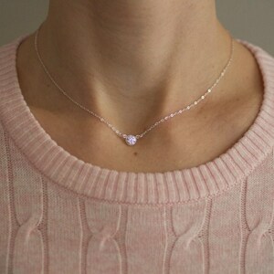 May include: A delicate silver chain necklace with a small, sparkly, round pendant.