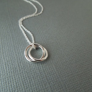 May include: A silver necklace with a delicate double circle pendant.