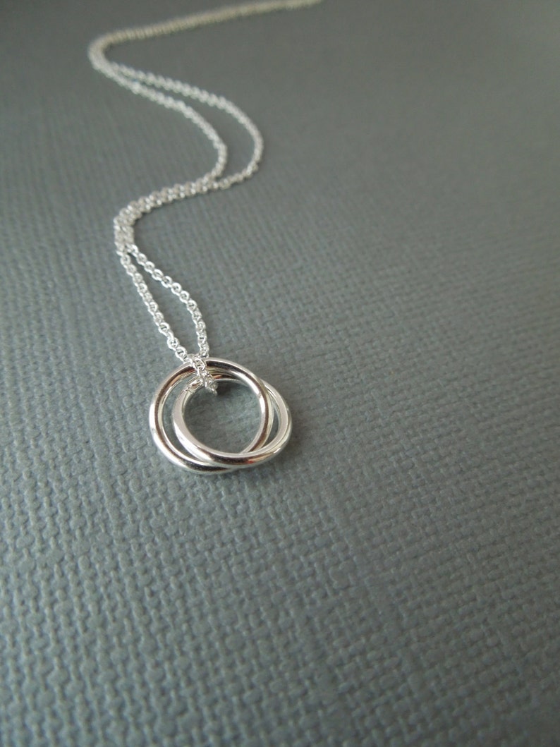 May include: A silver necklace with a delicate double circle pendant.