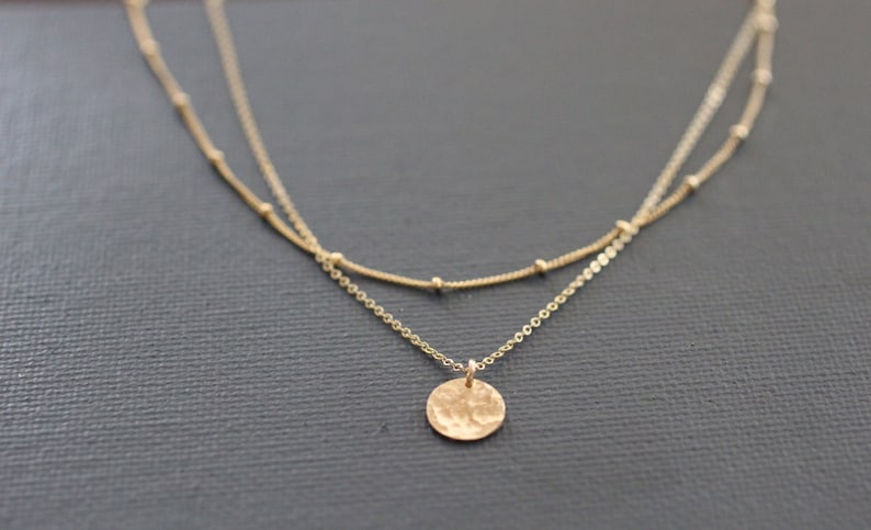 May include: A gold layered necklace with a hammered circle pendant.