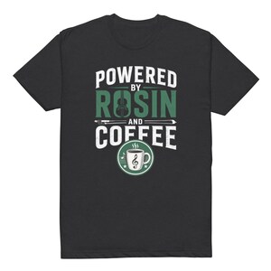 Può includere: T-shirt nero con la scritta "POWERED BY ROSIN AND COFFEE". Il design include un violino, un arco e una tazza di caffè con una nota musicale. Il testo e la grafica sono in bianco e verde.