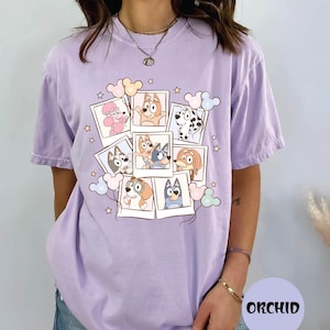 A woman wearing a purple t-shirt with a graphic design featuring cartoon dogs and other animals.