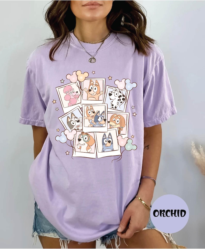 A woman wearing a purple t-shirt with a graphic design featuring cartoon dogs and other animals.