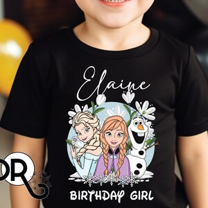 a young boy wearing a black shirt with a frozen princess picture on it