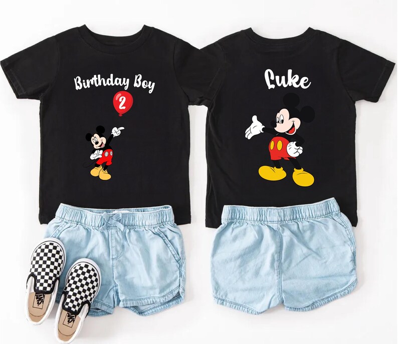 a pair of black t-shirts with Mickey Mouse designs, paired with denim shorts and checkered shoes, suggesting a birthday outfit for a child.