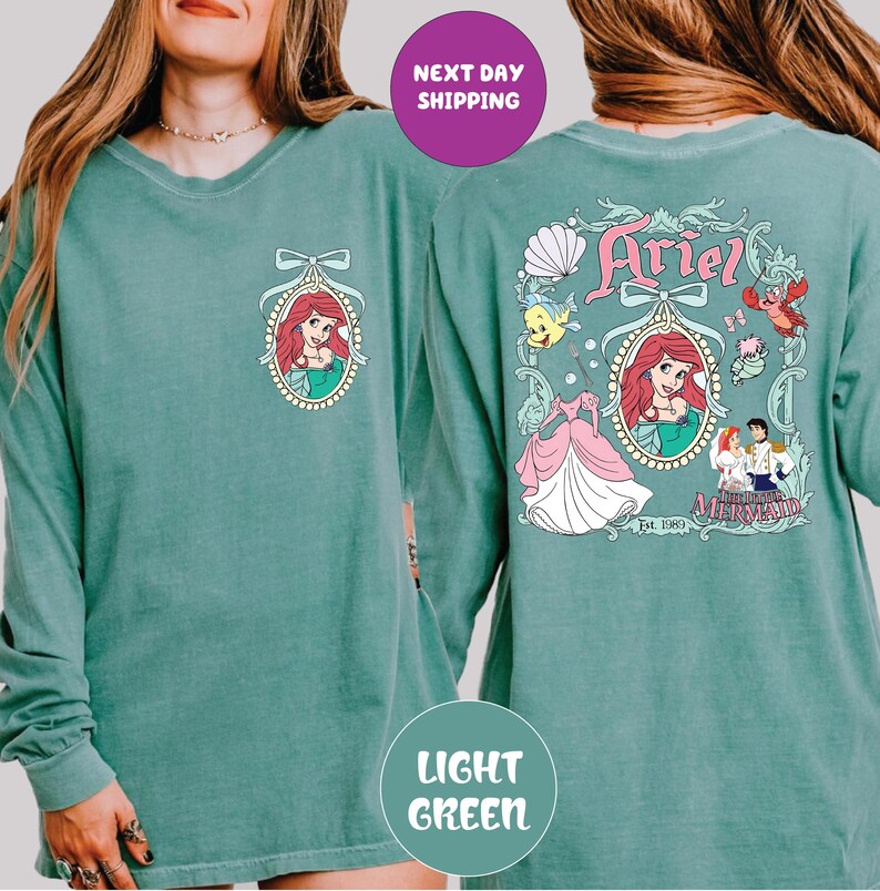 A woman wearing a green long-sleeved shirt with a graphic of Ariel from the Disney movie "The Little Mermaid".