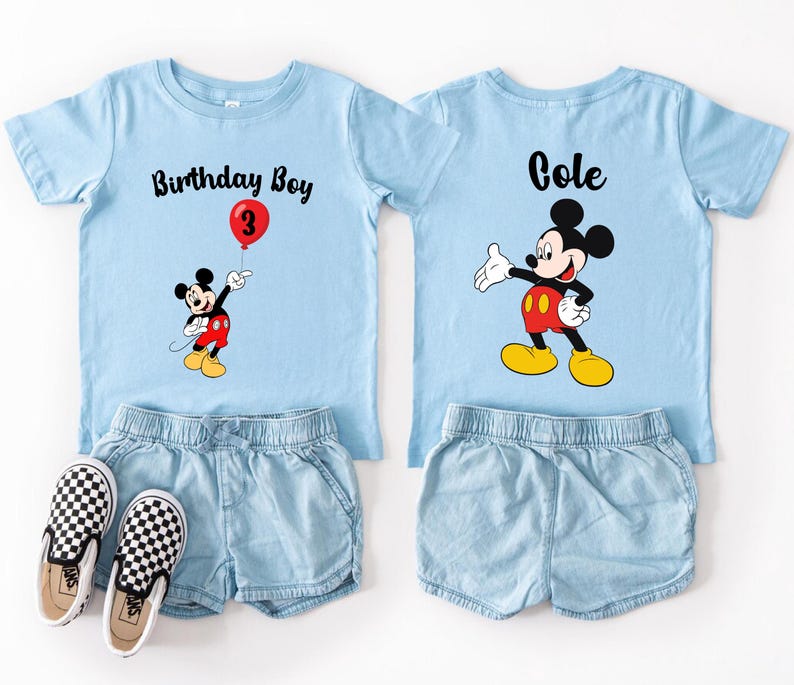 two blue t-shirts with Mickey Mouse designs, each with a personalized text and a balloon graphic, along with matching denim shorts and black and white checkered shoes.