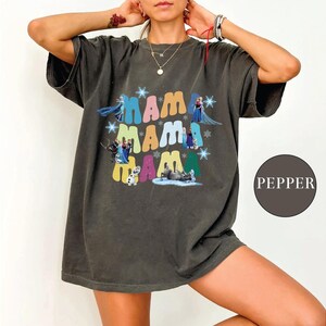 a woman wearing a gray shirt with the word mama on it