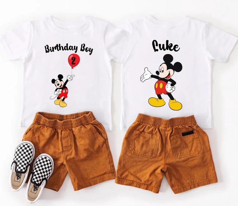 a pair of white t-shirts with Mickey Mouse designs, brown shorts, and a pair of black and white checkered shoes.