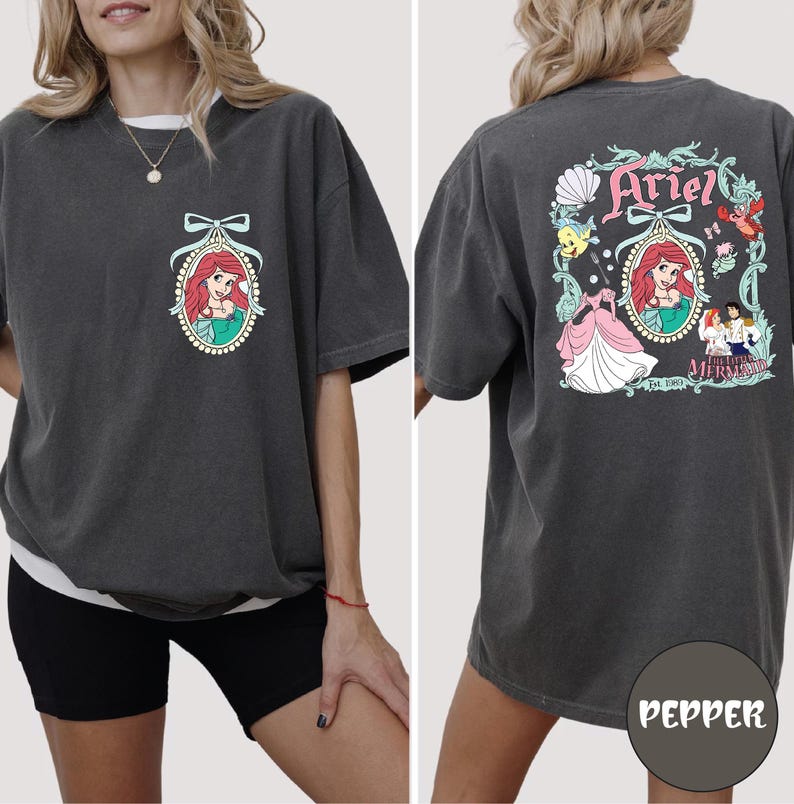 A woman wearing a gray t-shirt with a graphic of the Disney character Ariel from The Little Mermaid.