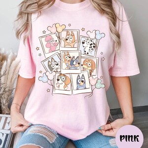 A woman wearing a pink t-shirt with a collage of cartoon animal characters and stars on it.
