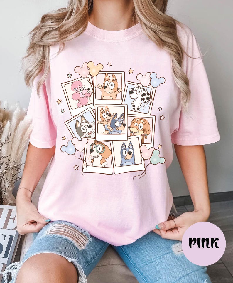 A woman wearing a pink t-shirt with a collage of cartoon animal characters and stars on it.