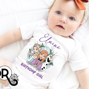 a baby laying on top of a bed wearing a white shirt