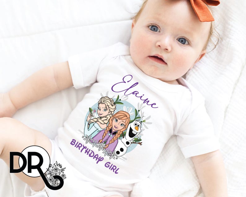 a baby laying on top of a bed wearing a white shirt