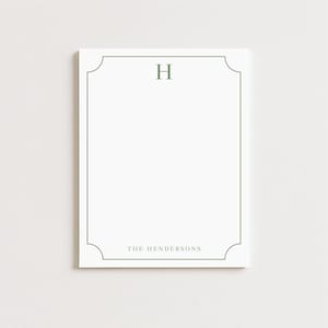 May include: White notepad with a green border and the letter "H" at the top. The text "THE HENDERSONS" is printed at the bottom. The notepad has a simple, elegant design.