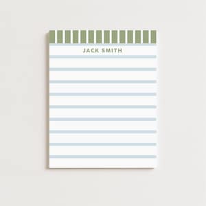 May include: A rectangular notepad with a white background and horizontal light blue stripes. The top edge features vertical green stripes. The text "JACK SMITH" is printed in a light green font above the horizontal stripes.