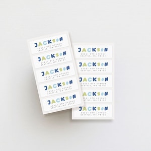 May include: Nine white rectangular address labels with blue and yellow rounded shapes spelling out the name "JACKSON" and the address "52561 8TH AVENUE SEATTLE, WA 98101".