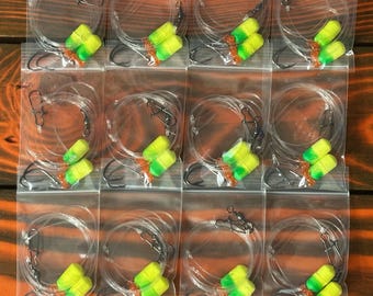 May include: Twelve clear plastic bags each containing a fishing lure with two yellow and green beads and a black hook.