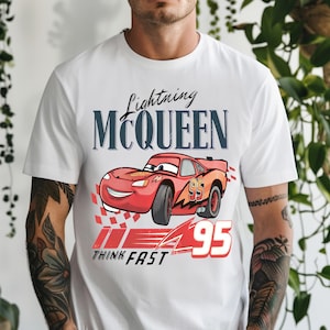 May include: White t-shirt featuring a graphic of Lightning McQueen from the Cars movie. The design includes the text "Lightning McQueen" above a red race car with the number "95" and the words "Think Fast".