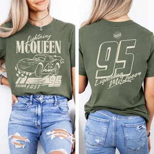 May include: Olive green t-shirt featuring Lightning McQueen from the Cars movie. The front graphic includes the character, the number 95, and the phrase "Think Fast." The back of the shirt displays the number 95 and "Lightning McQueen."