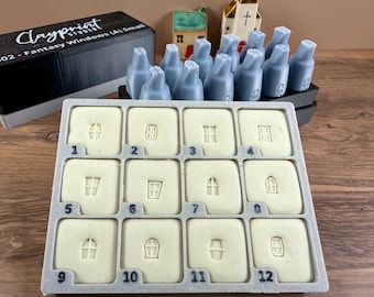 May include: A gray tray with twelve numbered, square molds, each featuring a different window design. The molds are for creating fantasy-themed windows. A black box with the text "Clayprint Studio" is in the background.