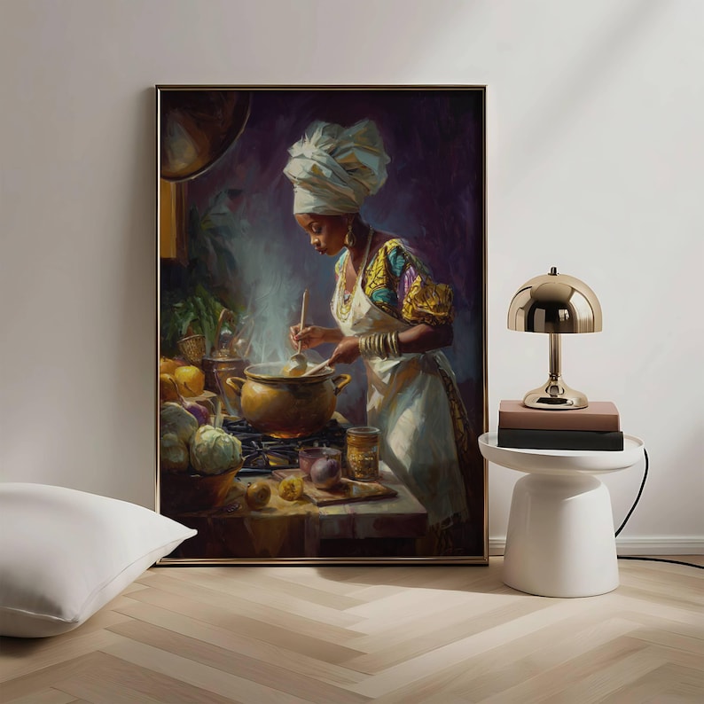 May include: A framed painting depicts a person in a white head wrap and apron stirring a pot on a stove. The person is wearing a colorful top and gold bracelets. A gold lamp sits on a white side table next to the painting.