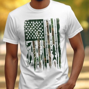 May include: A white t-shirt with a graphic of an American flag made up of fishing lures and camouflage print.