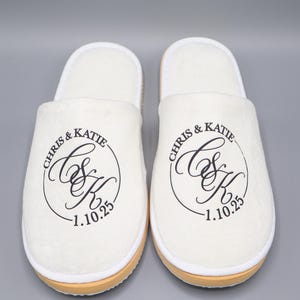 May include: A pair of white slippers with black embroidered text that reads "Chris & Katie C&K 1.10.25".